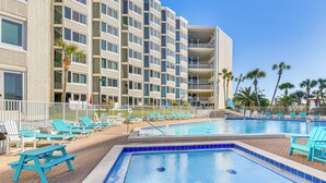 A hotel with a swimming pool, sun loungers, and a view of palm trees. - PCB Coastal Condo w/ On-site Beach Access! (Panama City Beach)