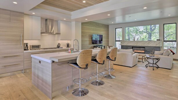 A modern kitchen with a central island, bar stools, a sofa, and a fireplace. - Luxurious Home, Walk to Beaver Creek Gondola! (Avon)
