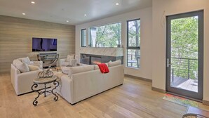 A modern living room with a sofa, a fireplace, a television, and large windows. - Luxurious Home, Walk to Beaver Creek Gondola! (Avon)