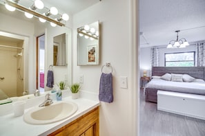 A modern bathroom with a large mirror, vanity, and a shower area.