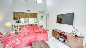 Una sala de estar moderna con un sofá rosa, un mueble de madera y un televisor de pantalla plana.
