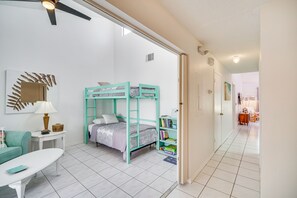 A room with a bunk bed, a desk, a chair, a lamp, and a bookshelf.