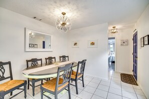 A dining area with a round table, six chairs, and a chandelier.