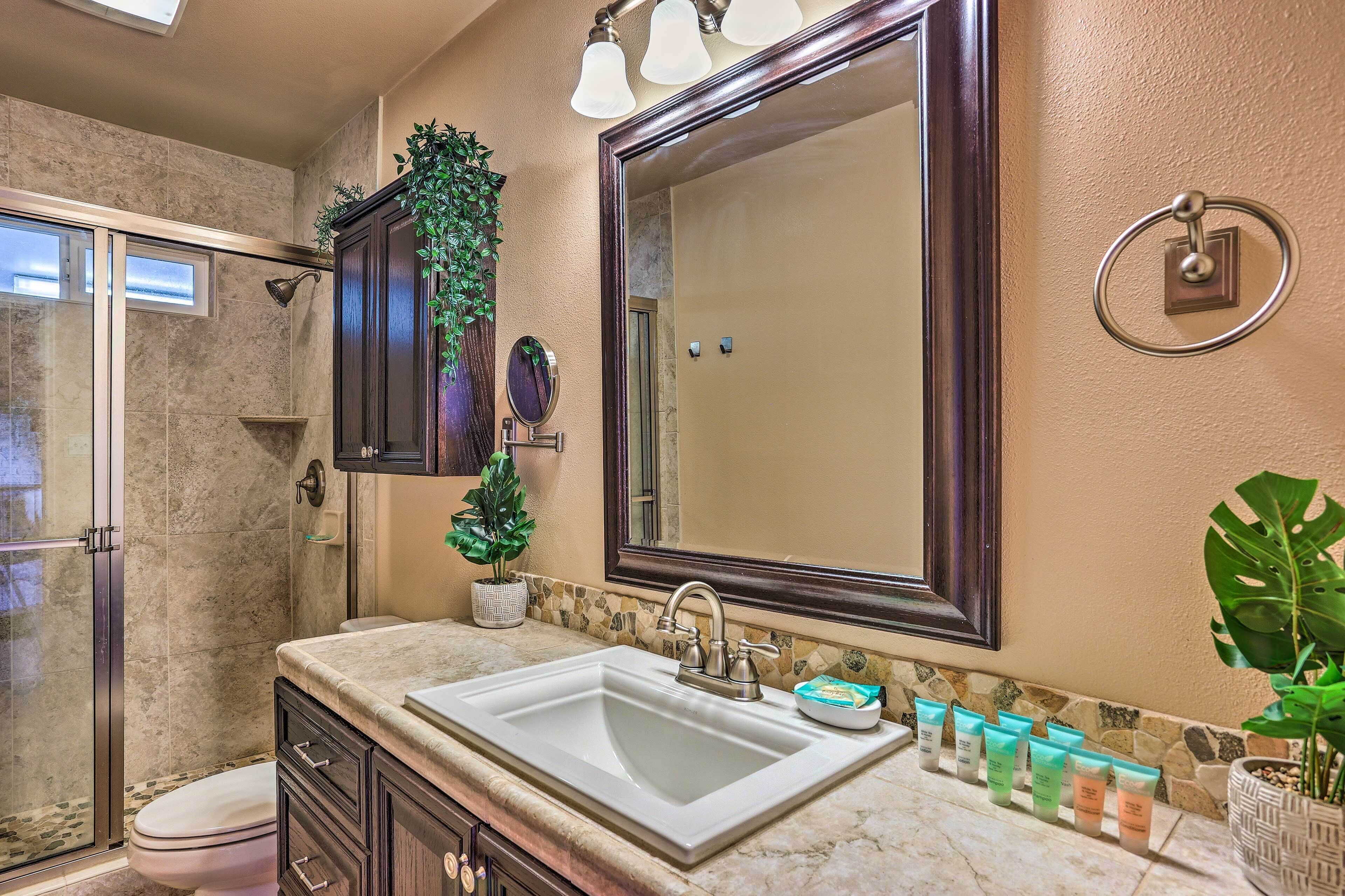 A bathroom with a large mirror, a sink, and a shower area.