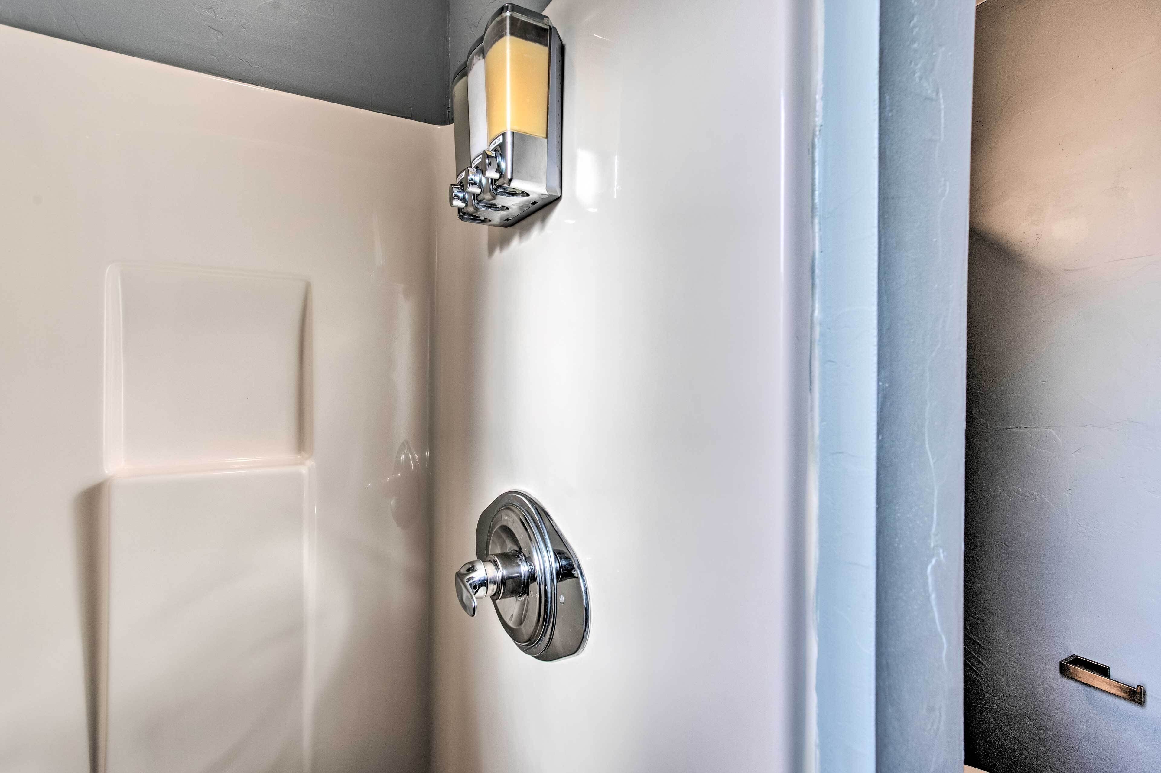 Un bagno con una porta bianca, una maniglia cromata e un lampadario a parete.