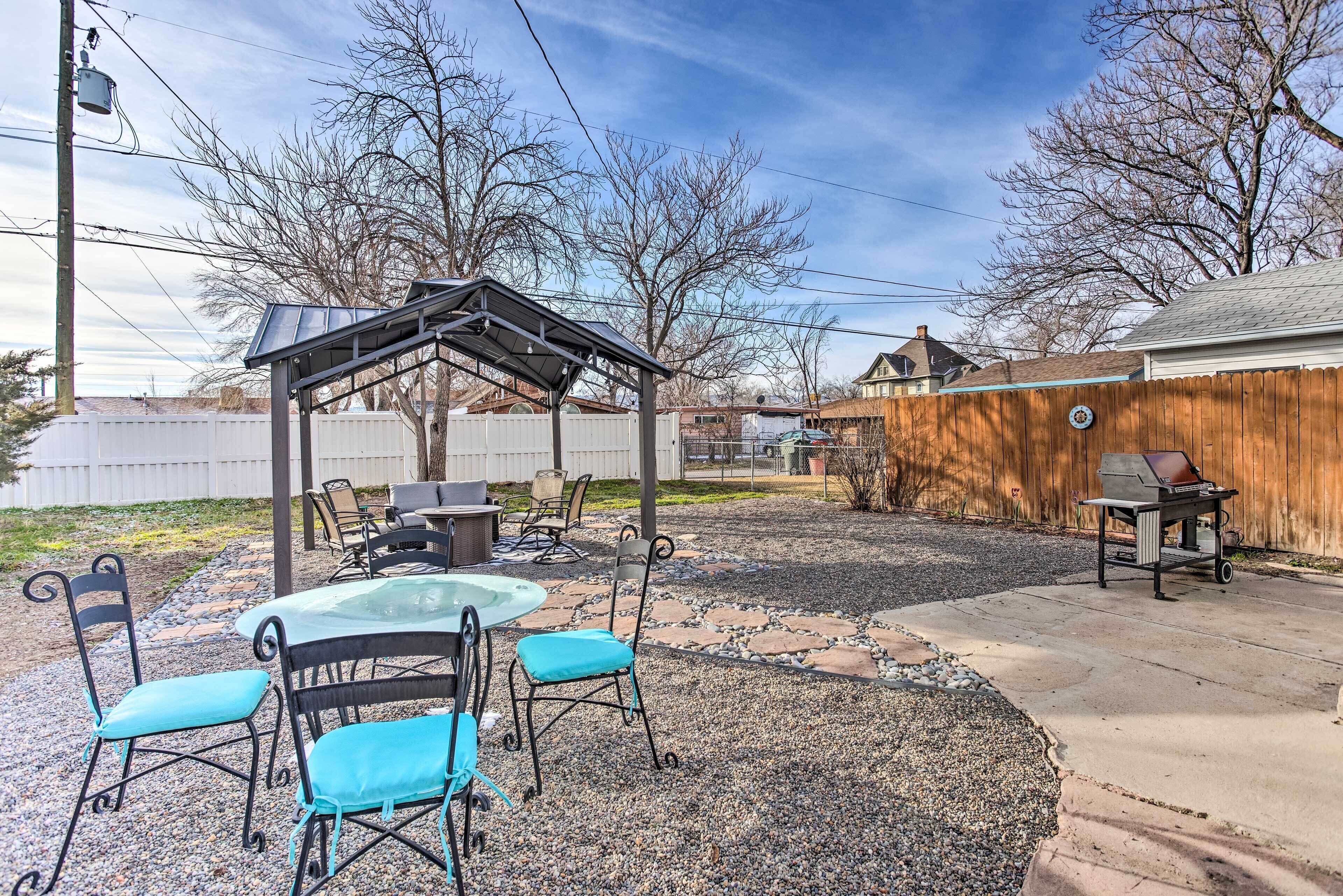 Un patio à l’arrière de la maison, agrémenté d’une pergola, de meubles d’extérieur et d’un barbecue.
