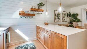 A kitchen with wooden cabinets, a white countertop, and pendant lighting.