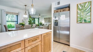 A modern kitchen with a stainless steel refrigerator, wooden cabinets, and a white countertop.