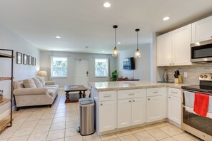 A modern kitchen with white cabinets, a stainless steel stove, and a large island.