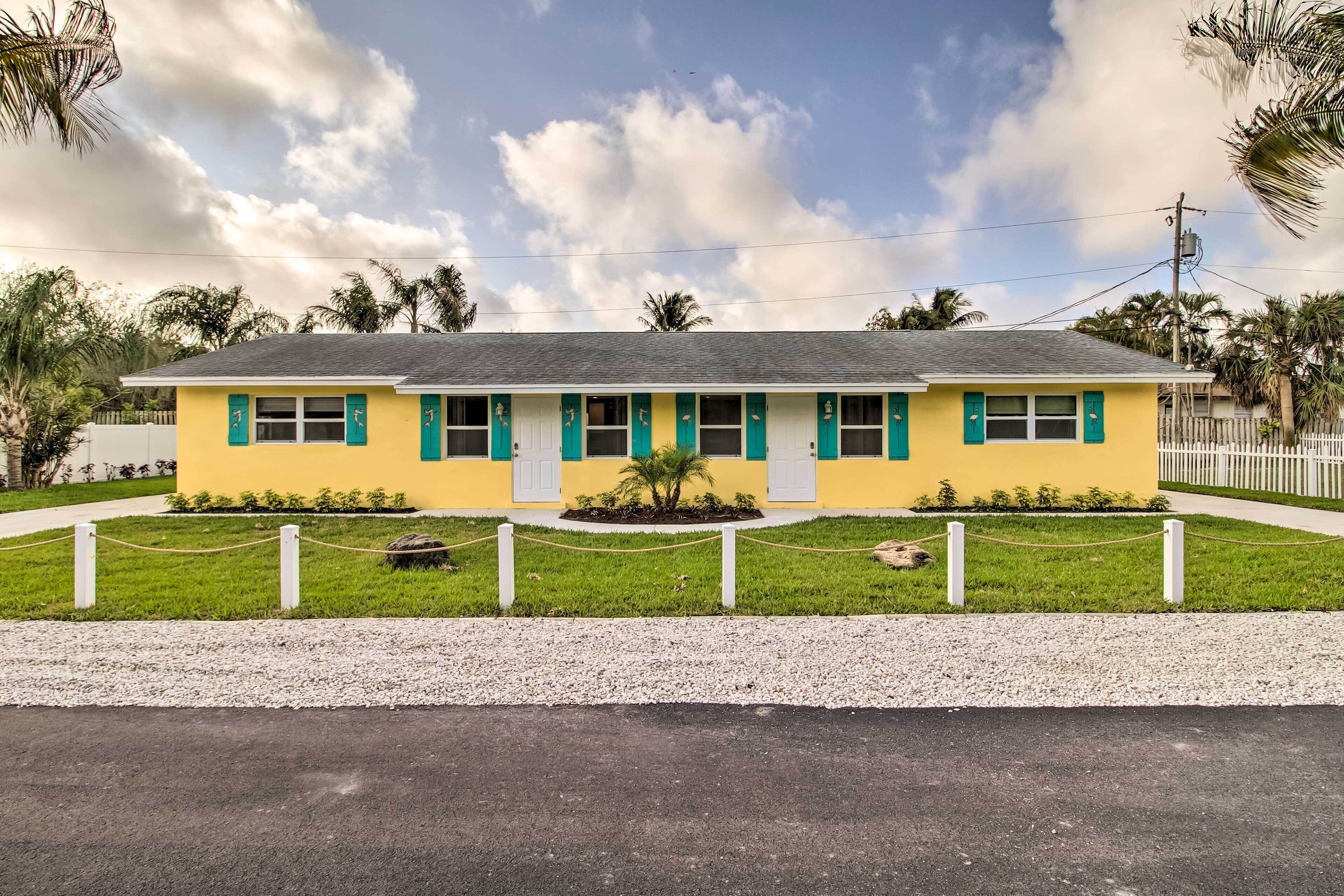 A yellow building with teal shutters and a gravel driveway.