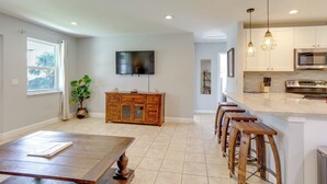 A modern kitchen with a large island, wooden bar stools, and a flat-screen TV mounted on the wall. - < 3 Mi to Juno Beach: Coastal Townhome w/ Patio! (Juno Beach)