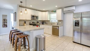 A modern kitchen with white cabinets, stainless steel appliances, and a central island with stools. - < 3 Mi to Juno Beach: Coastal Townhome w/ Patio! (Juno Beach)