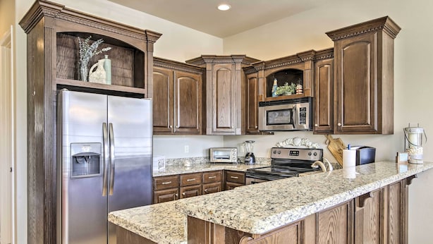 A kitchen with dark wood cabinets, stainless steel appliances, and a granite countertop.