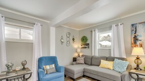 Un salon avec un fauteuil bleu, un canapé gris et une petite table sur laquelle se trouvent un globe terrestre et des objets décoratifs.