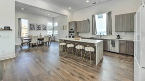 A modern kitchen with a central island, bar stools, and a dining area with a table and chairs. - Luxurious & Spacious Austin Home ~ 8 Mi to Dtwn! (Austin)