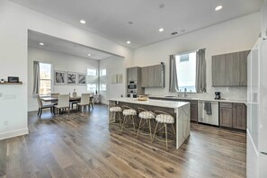 A modern kitchen with a central island, bar stools, and a dining area with a table and chairs. - Luxurious & Spacious Austin Home ~ 8 Mi to Dtwn! (Austin)