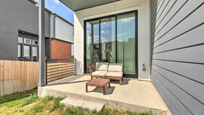 A patio with a wooden table and two chairs, a sliding glass door, and a covered area with a roof. - Luxurious & Spacious Austin Home ~ 8 Mi to Dtwn! (Austin)