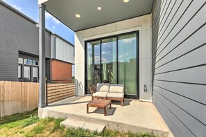 A patio with a wooden table and two chairs, a sliding glass door, and a covered area with a roof. - Luxurious & Spacious Austin Home ~ 8 Mi to Dtwn! (Austin)