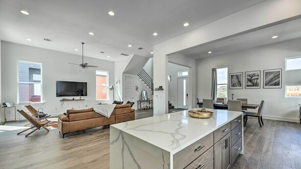 A spacious living area with a large island, a brown sofa, and a ceiling fan. - Luxurious & Spacious Austin Home ~ 8 Mi to Dtwn! (Austin)