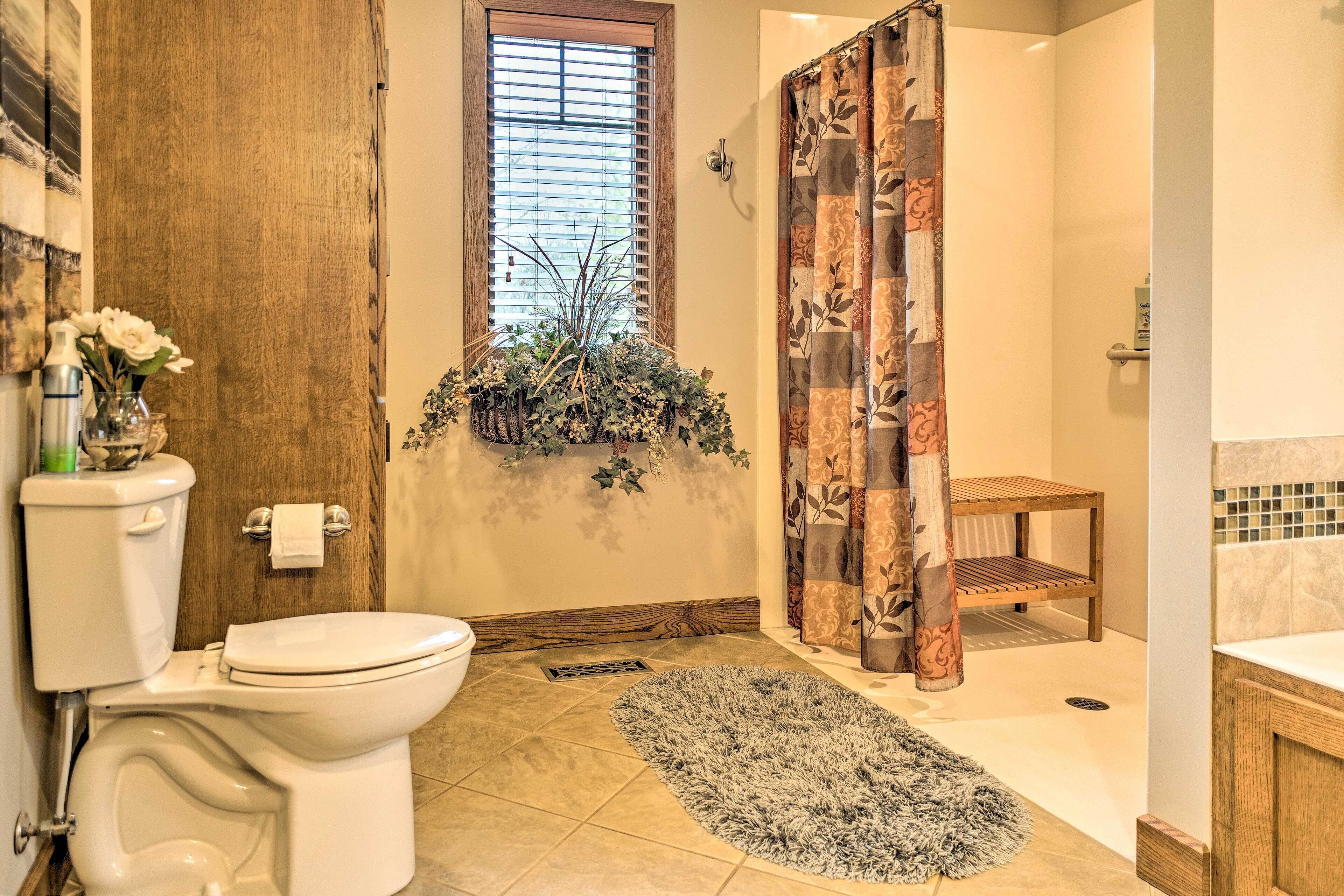A bathroom with a toilet, shower curtain, and a small shelf with plants.