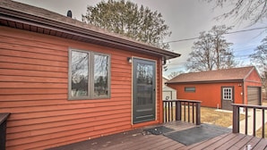 Ett rött trähus med en veranda på framsidan, ett garage och en liten uteplats.