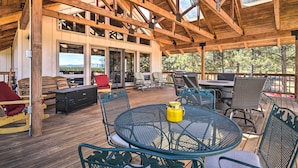 Une terrasse extérieure avec des poutres en bois, une table à manger, des chaises et un espace barbecue.