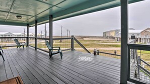 Eine überdachte Veranda mit Holzboden, Metallgeländern und zwei Adirondack-Stühlen.