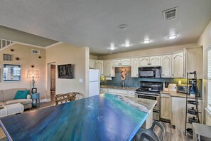 A modern kitchen with a central island, wooden cabinets, and a microwave. - Idyllic Gulf Coast Escape: Steps to Surfside Beach (Freeport)