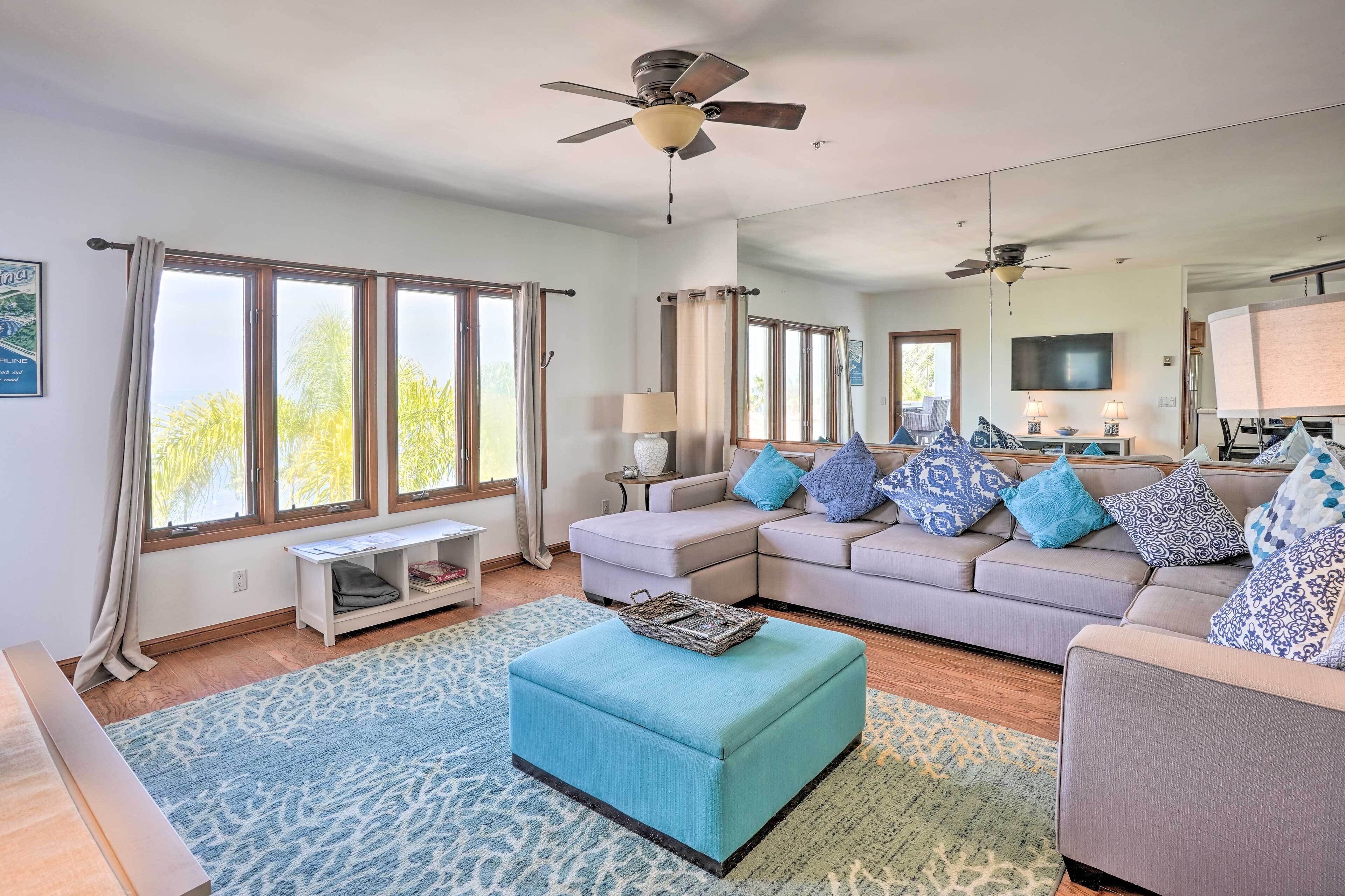 A spacious living room with a large sofa, ottoman, and a ceiling fan.