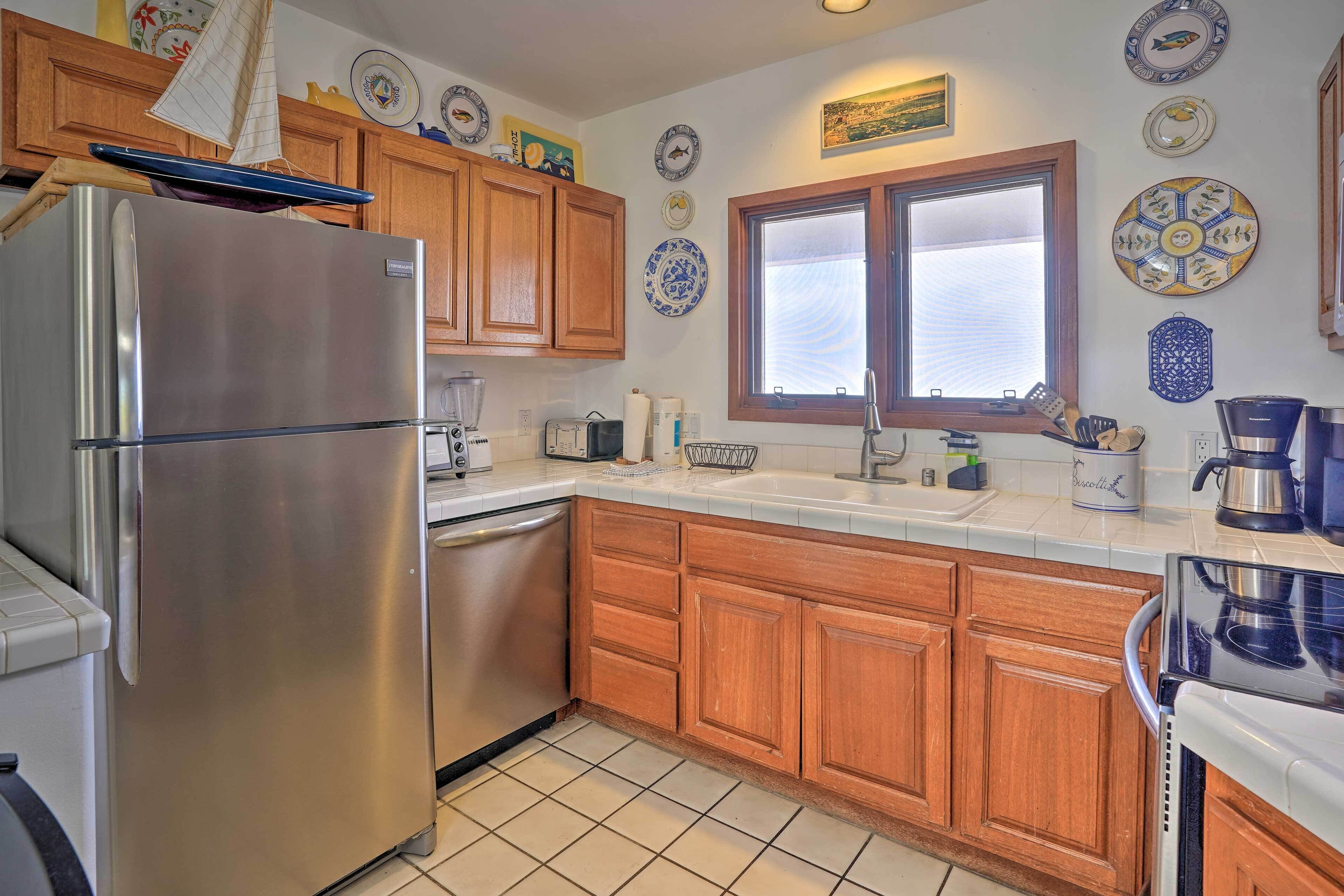 A kitchen with wooden cabinets, a stainless steel refrigerator, a sink, and various kitchen appliances.