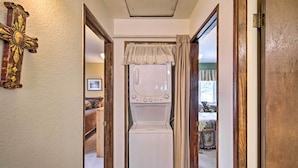 A laundry room with a front-loading washing machine, wooden doors, and a decorative cross on the wall. - 3 Mi to Skiing: Big Bear Cabin w/ Deck (Big Bear City)