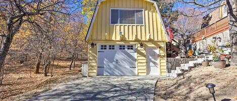 A yellow building with a garage, surrounded by trees and a clear sky.