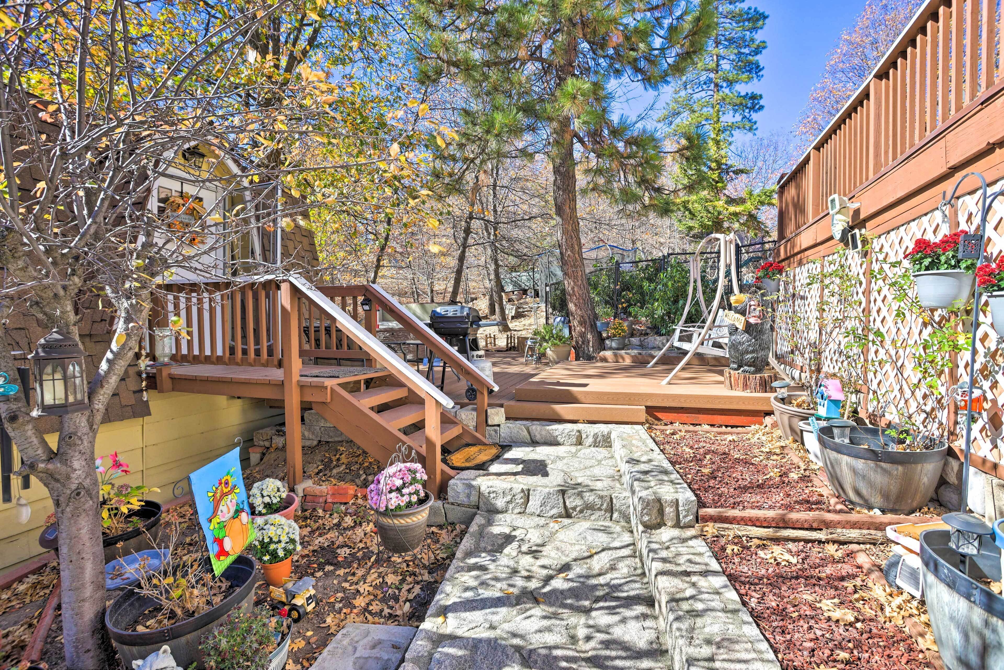 A backyard with a wooden staircase, stone steps, potted plants, and a wooden deck.