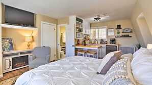 A cozy bedroom with a large bed, a TV, a fireplace, and a kitchenette in the background. - Lake Arrowhead Studio Near Hiking w/ Hot Tub (Lake Arrowhead)