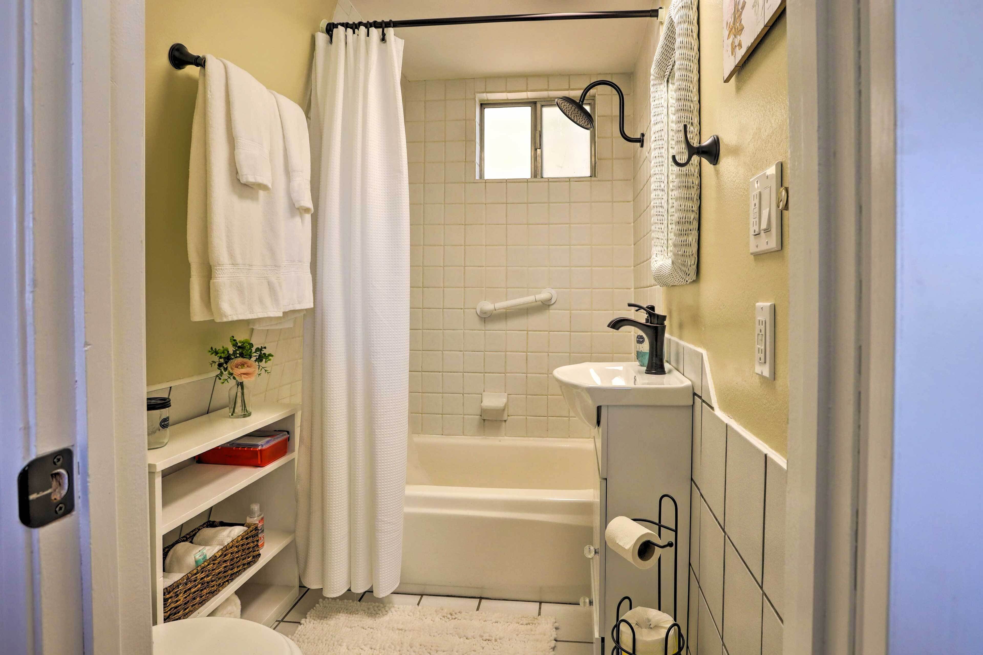 A small, clean bathroom with a bathtub, a toilet, a sink, and a shower curtain.