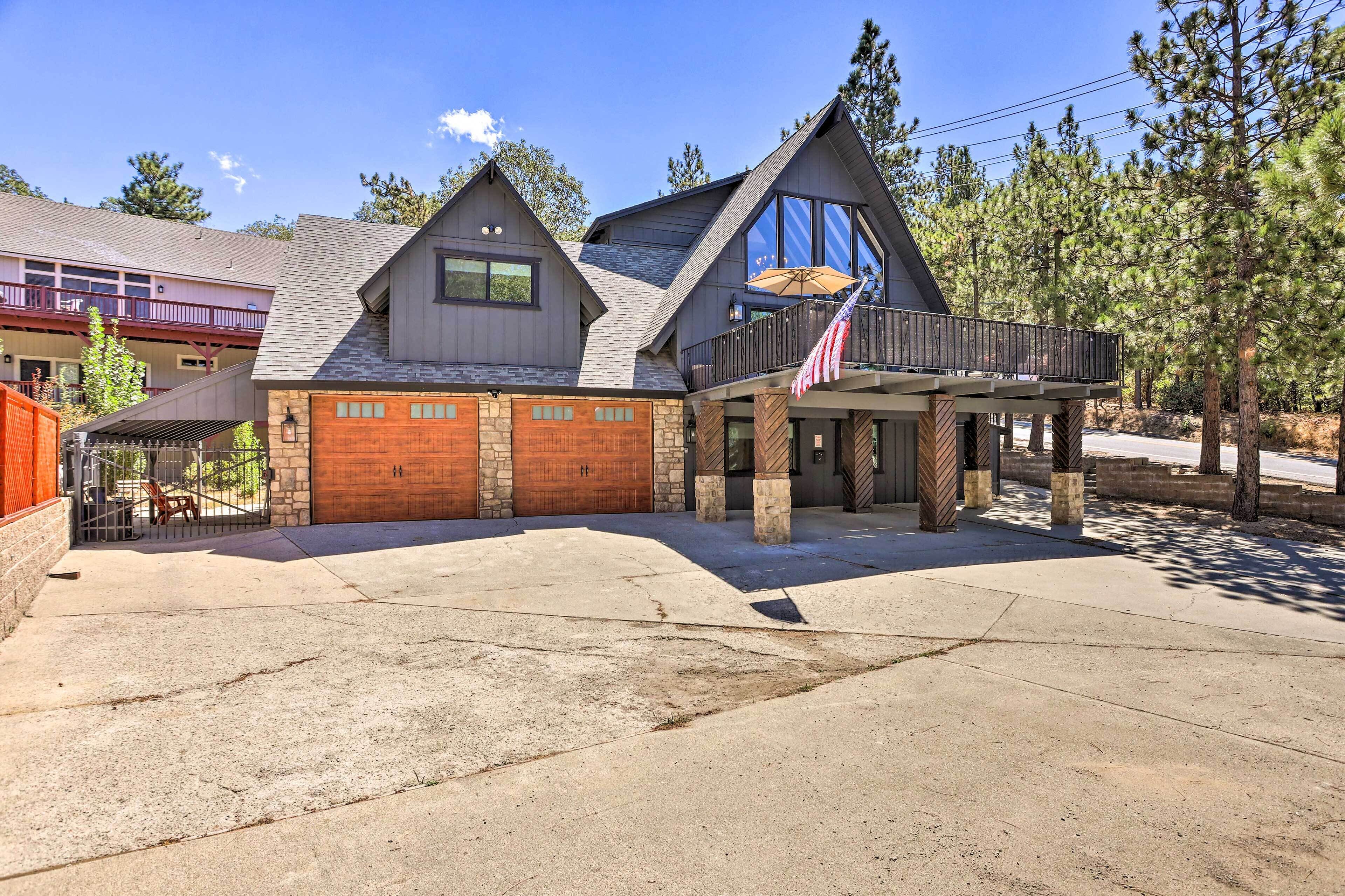 A two-story house with a stone facade, a wooden garage door, and a balcony with an American flag.