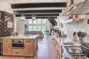 A modern kitchen with a central island, wooden cabinets, and a large window providing natural light.