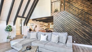 A modern living room with a sectional sofa, a coffee table, and a staircase leading to an upper level. - Luxe Timberland Villa w/ Lake Arrowhead Access! (Lake Arrowhead)