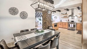A modern dining area with a wooden table, dark chairs, and a geometric pendant light. - Luxe Timberland Villa w/ Lake Arrowhead Access! (Lake Arrowhead)