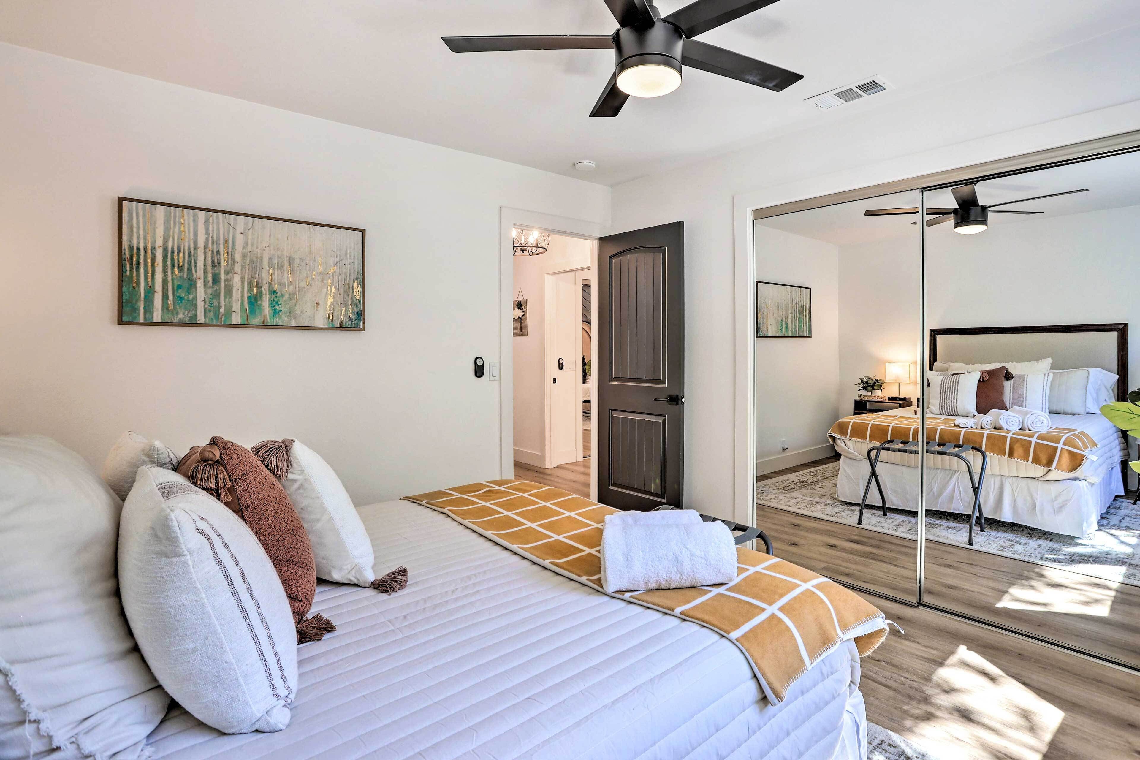 Un dormitorio moderno con una cama grande, un ventilador de techo y un espejo que refleja la habitación.