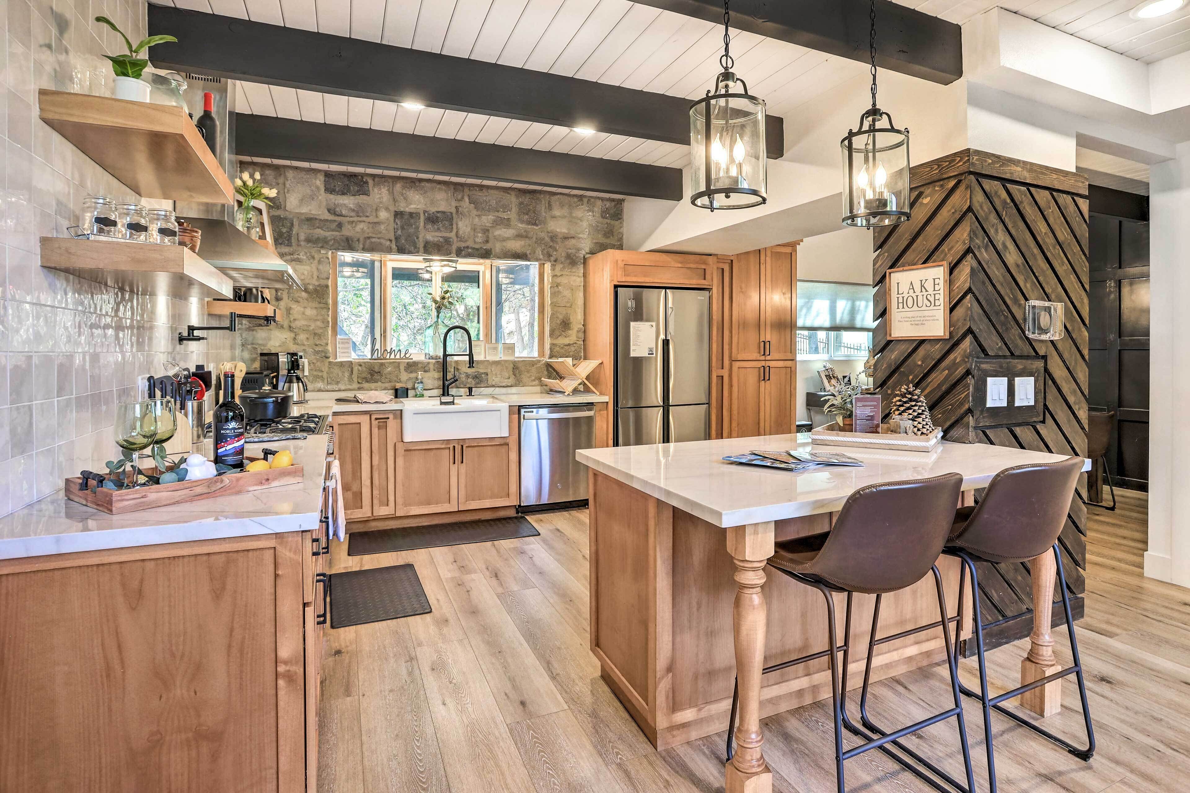 A modern kitchen with wooden cabinets, a central island, bar stools, and a herringbone-patterned accent wall.