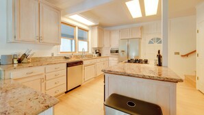 Una cucina moderna con mobili in legno chiaro, un'isola centrale ed elettrodomestici integrati.