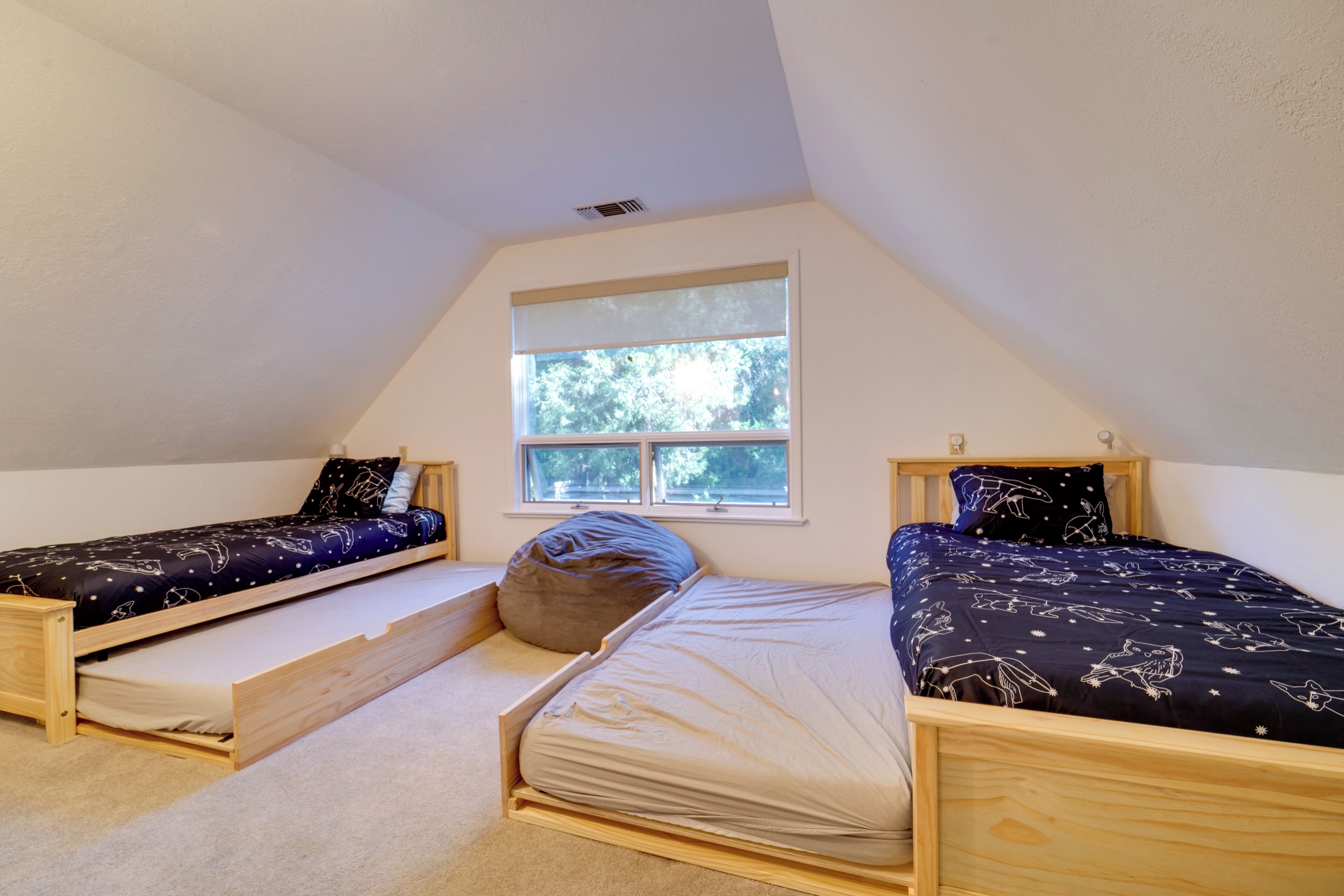 A dorm-style room with two wooden beds, a window, and a built-in bench.