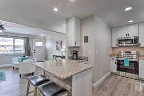 Una cocina moderna con encimeras de granito, electrodom ésticos de acero inoxidable y una isla central con taburetes de bar.