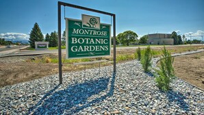 A sign for Montrose Botanical Gardens with a clear sky and a gravel path.