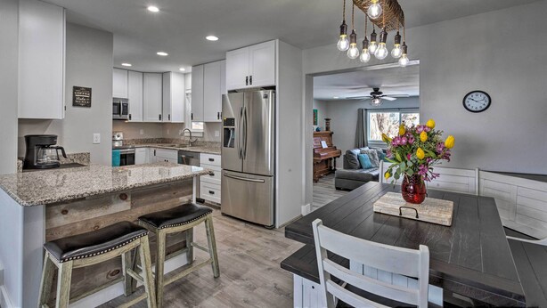 A modern kitchen with white cabinets, a stainless steel refrigerator, and a dark wooden island with bar stools.