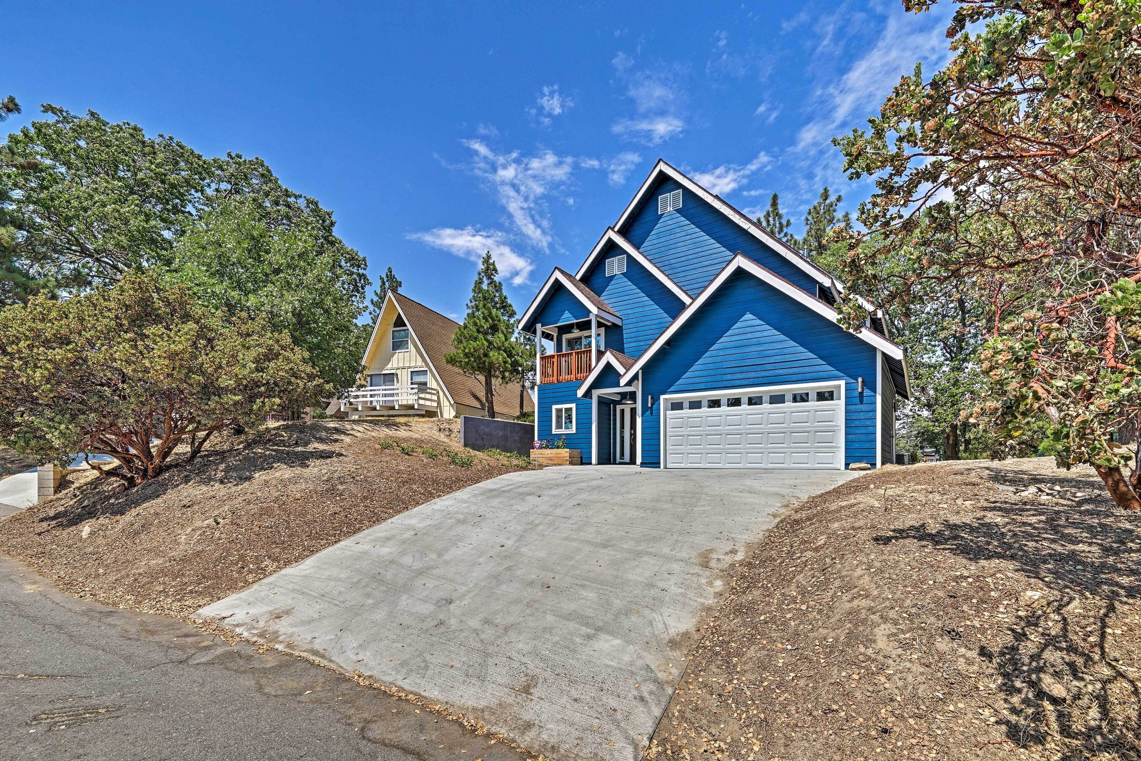 A two-story house with a blue exterior, a front garage, and a driveway leading to the entrance.