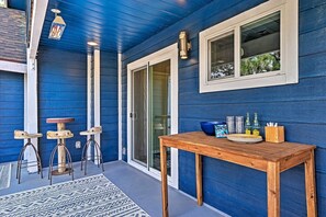A covered patio with a wooden table, two stools, and a lantern.