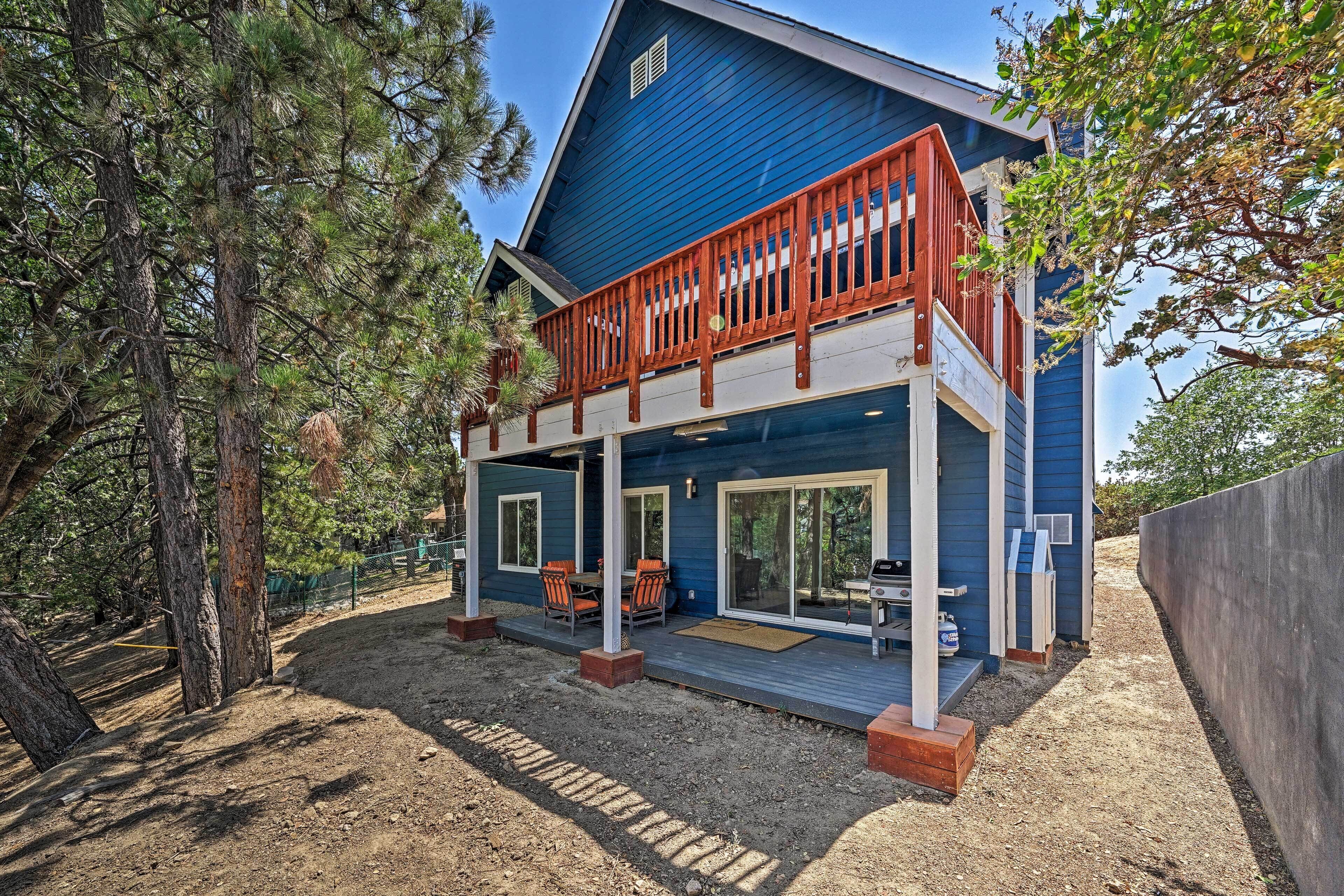 A two-story house with a blue exterior, a wooden balcony, and a covered patio area.