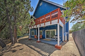 A two-story house with a blue exterior, a wooden balcony, and a covered patio area.